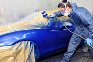 A man using paint tool to apply blue color on the car exterior