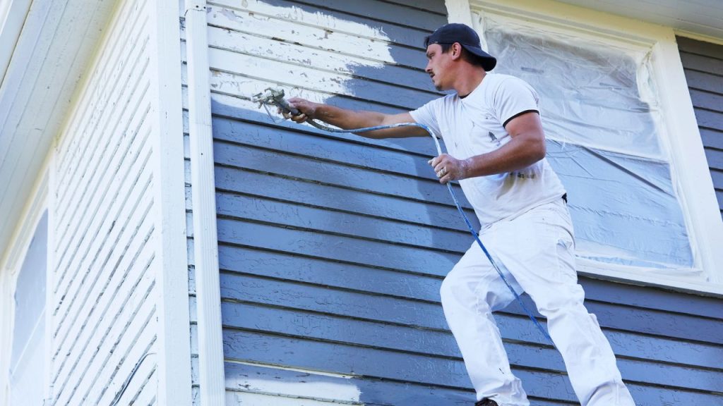 a paint technician carefully doing exterior painting